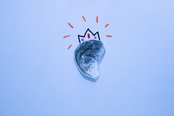 A cutout drawing of an oyster placed on a whiteboard with a sparkly crown drawn above it