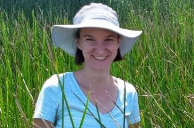 Genevieve Noyce in white hat on wetland