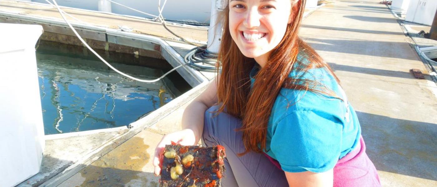 Woman on docks holding tile with marine life